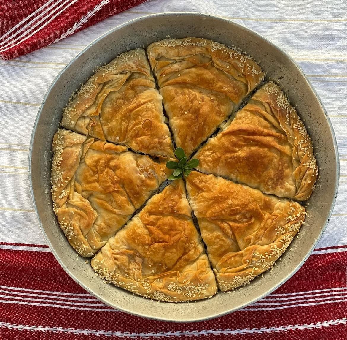 Round tray of layered byrek cut into wedges