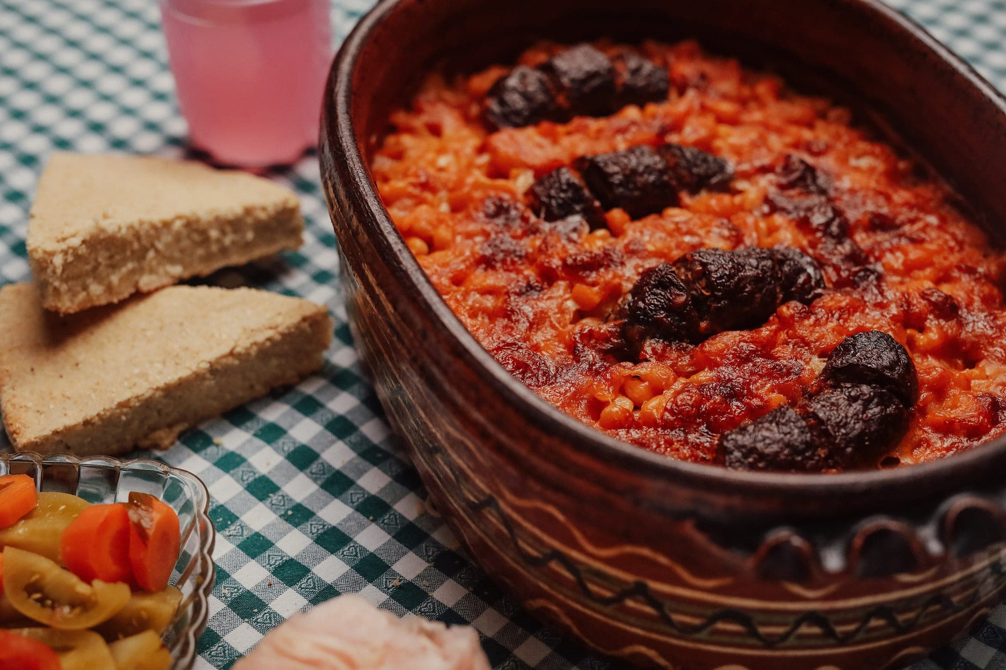 Baked beans with sausage in a clay dish, the kind of slow-cooked Balkan dish served at a family table